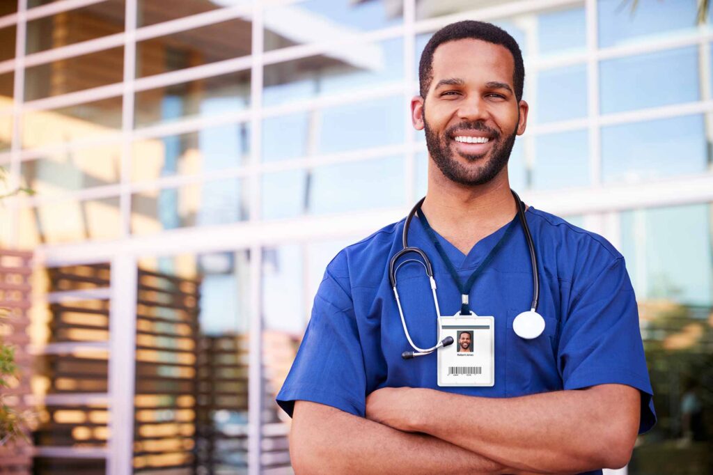 A male doctor with crossed arms smiling into the camera.