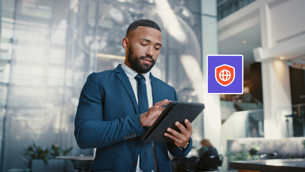 A man in a suit uses a tablet in a modern office lobby. The image features a digital icon with a globe and shield.