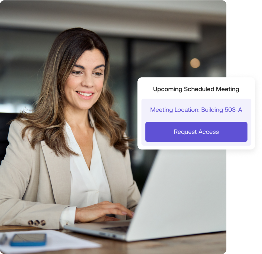 Woman in an office smiles while using a laptop. A digital notification nearby displays details for an upcoming scheduled meeting with a Request Access button.