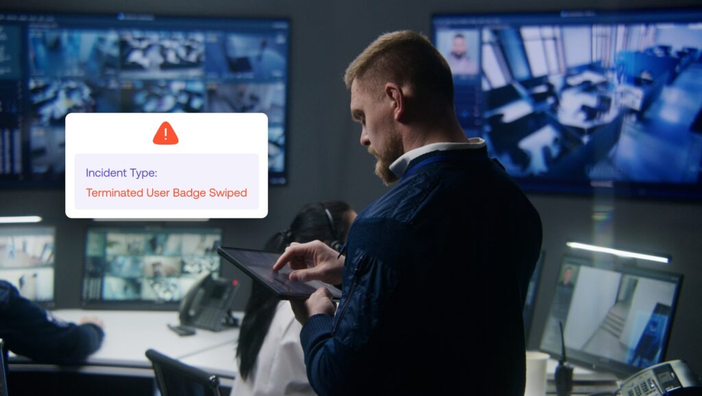 A man uses a tablet in a security control room showing multiple surveillance monitors; an alert on screen reports a Terminated User Badge Swiped incident.