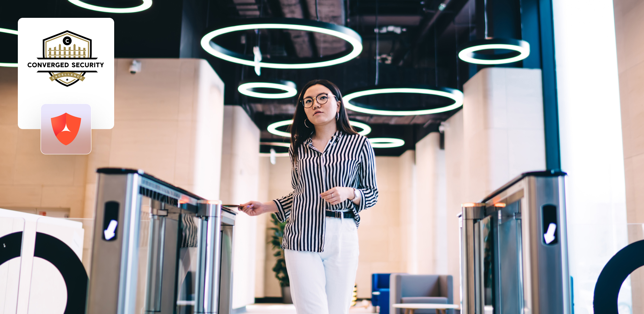 A woman in business attire walks through a secure entry gate in a modern office lobby, with security badges and LED ceiling lights visible.