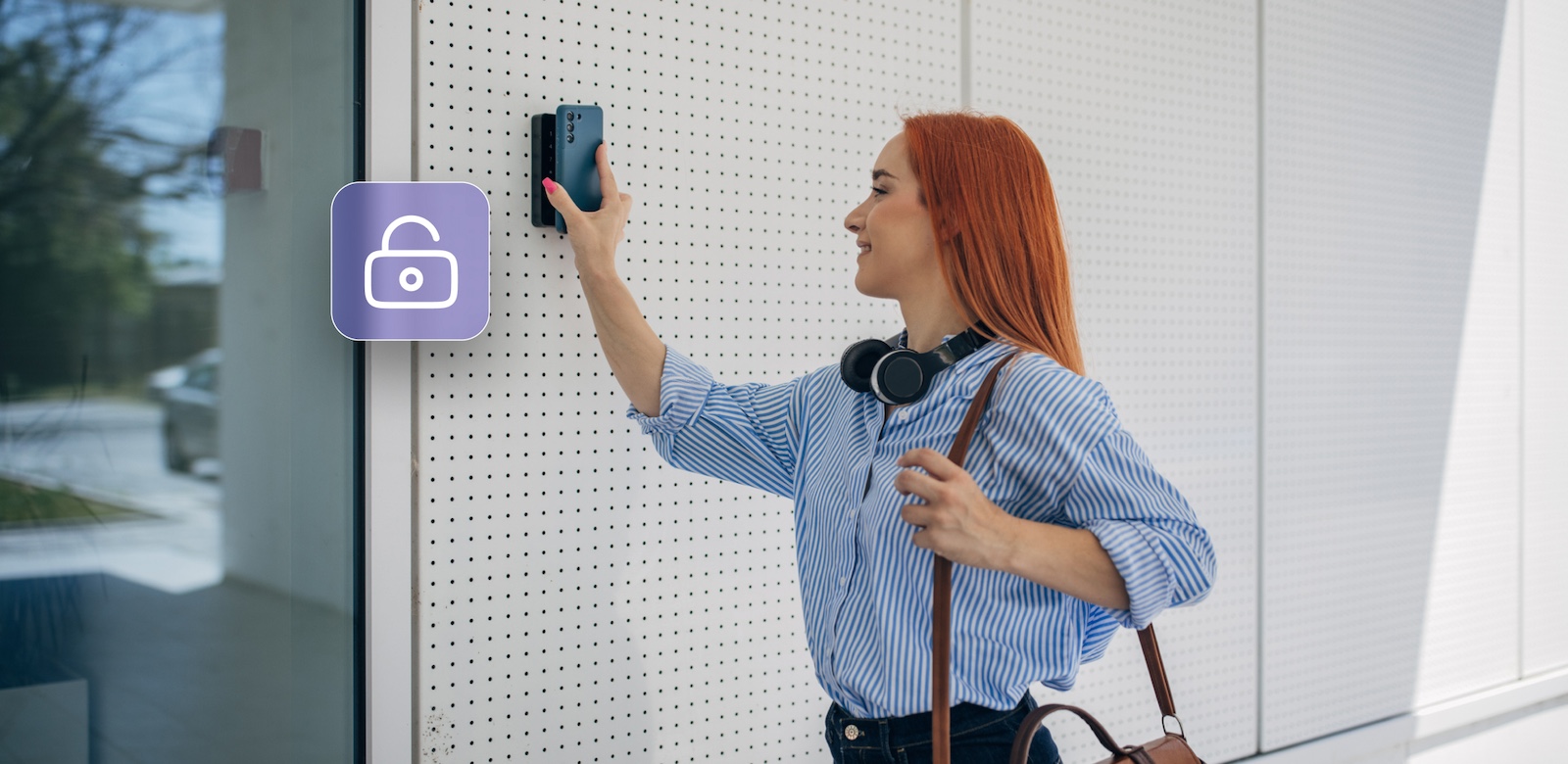 A woman holds her smartphone up to a wall-mounted access control device, unlocking a door as indicated by an open lock icon on the wall.