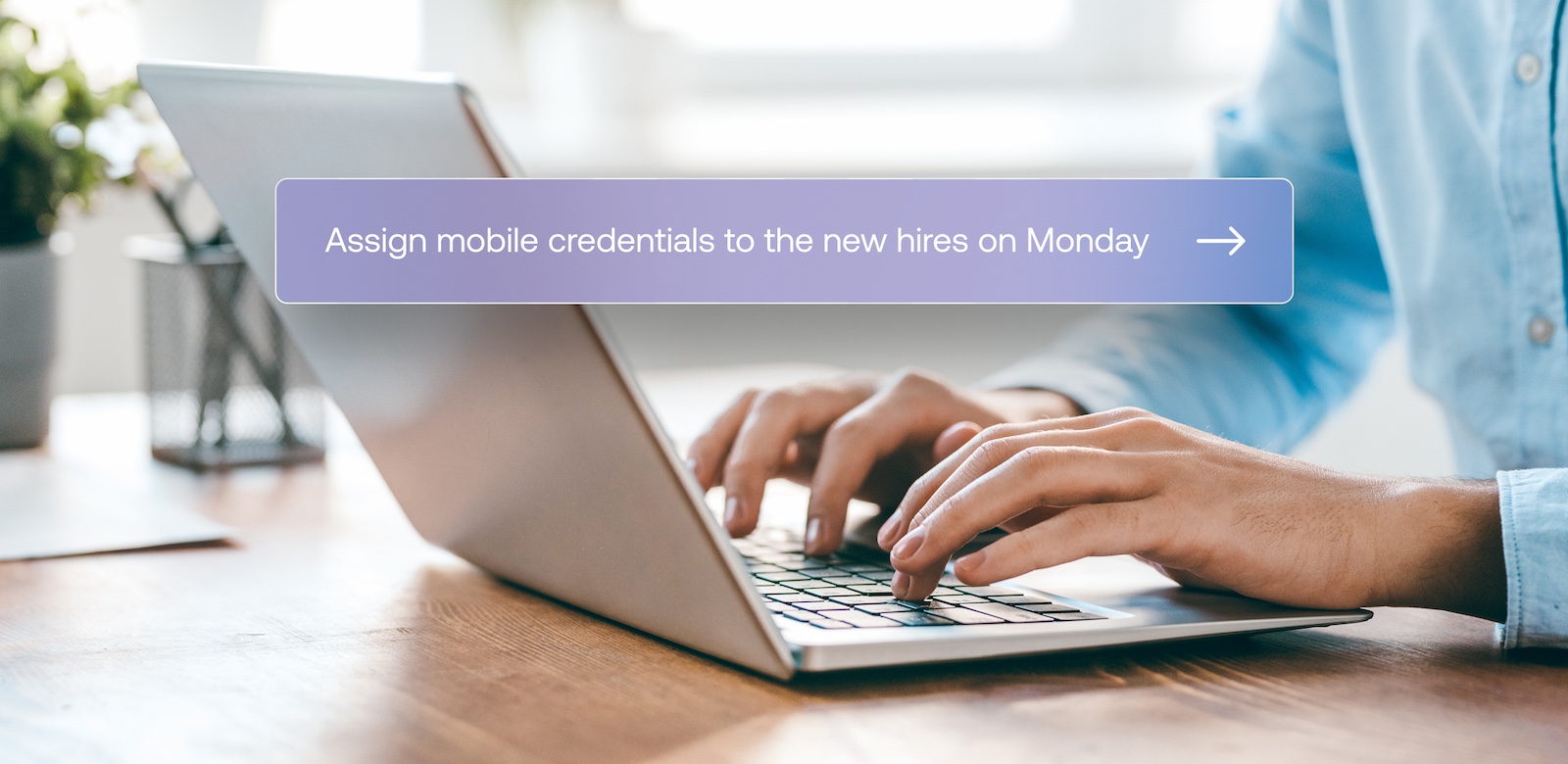 Person typing on a laptop with an on-screen reminder that says, Assign mobile credentials to the new hires on Monday.