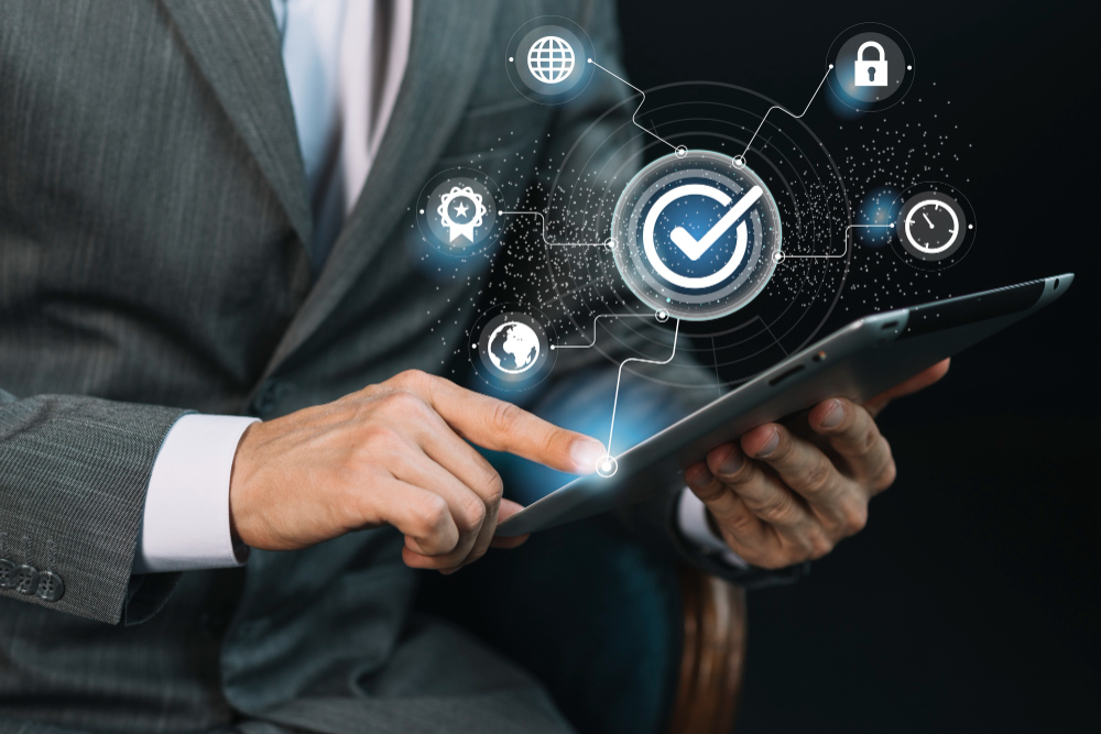 A person in a suit uses a tablet, with digital icons for security, internet, and efficiency floating above, representing technology and data protection concepts.