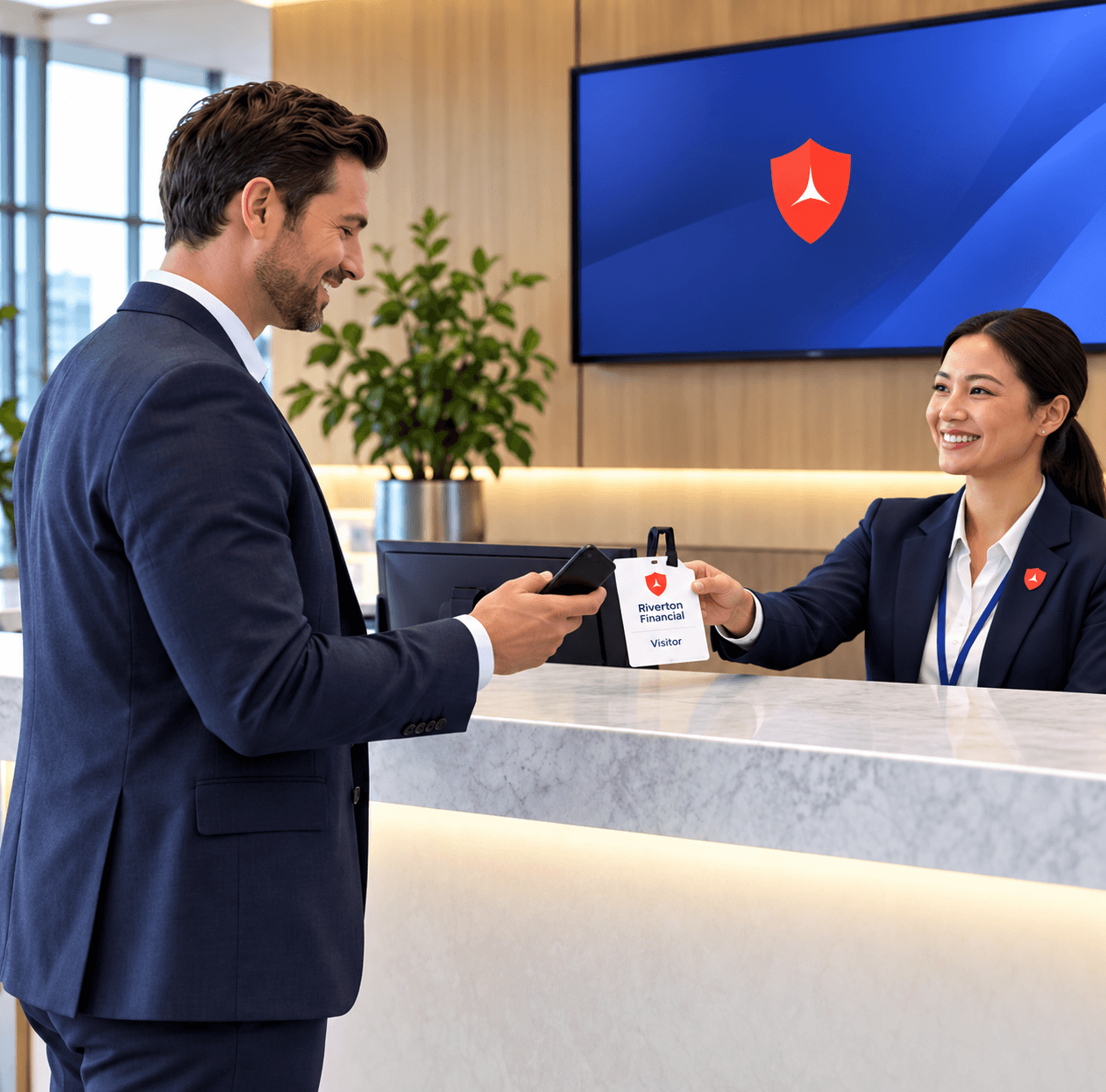 A man in a suit checks in at a reception desk, receiving a visitor badge from a smiling receptionist. A blue security logo is displayed on a screen in the background.