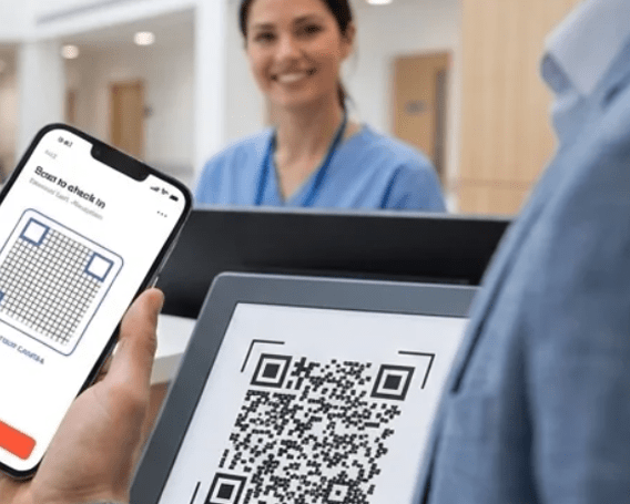 A person scans a QR code on a tablet using a phone, while a healthcare worker in scrubs smiles in the background at a reception desk.
